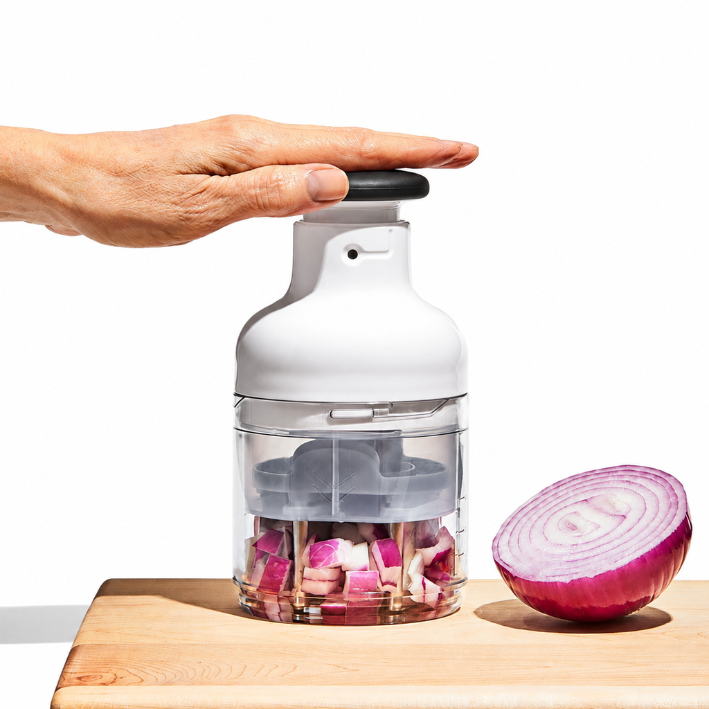 Hand using the chopper with onion in the clear cup